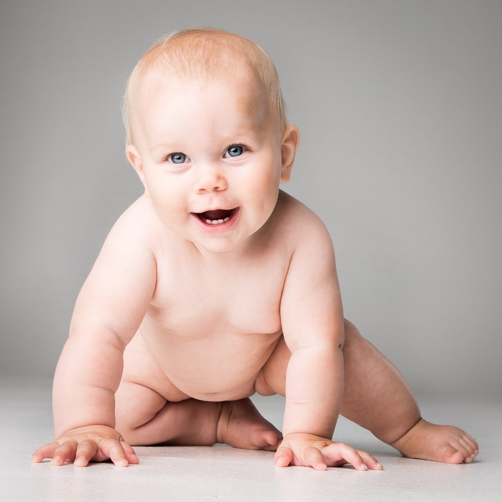 glad naken bebis med blåaögon poserar för en bild